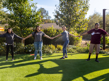 Four students participating in a group exercise by joinging hands.