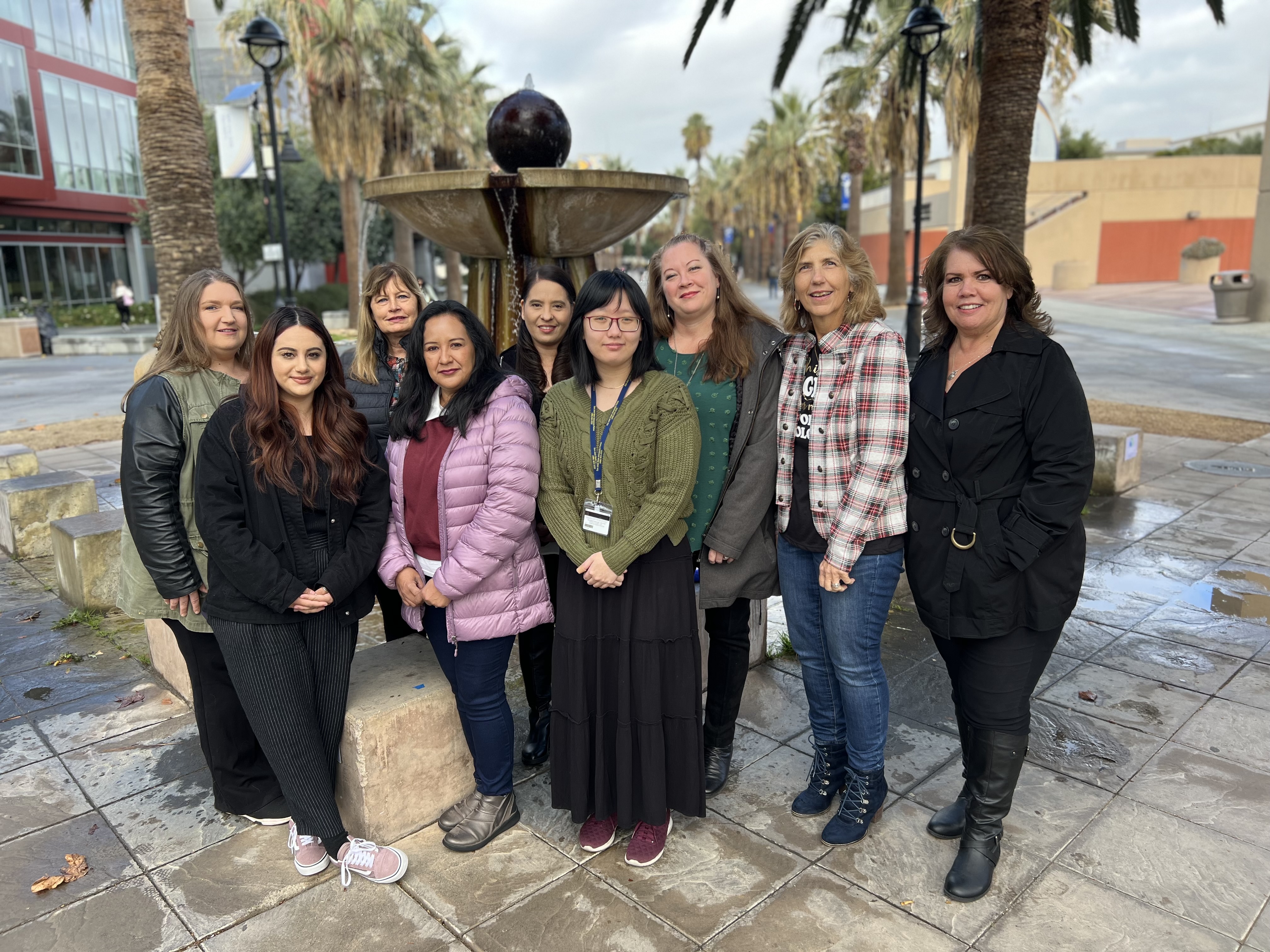 Image of nine women in front of a fountain, smiling