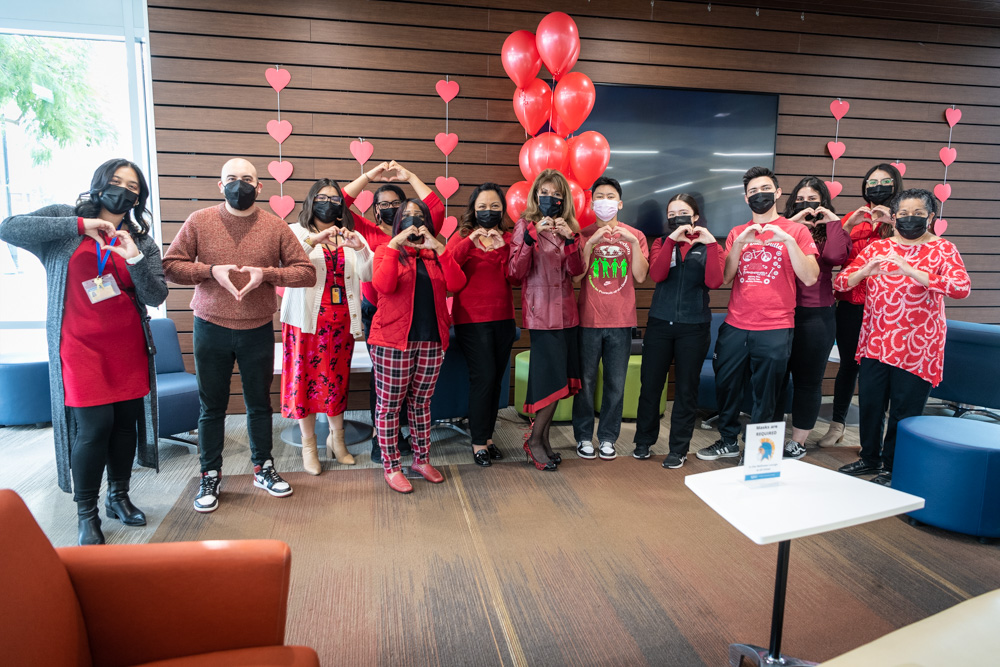 九州体育 president with students and staff making a heart sign with their hands.